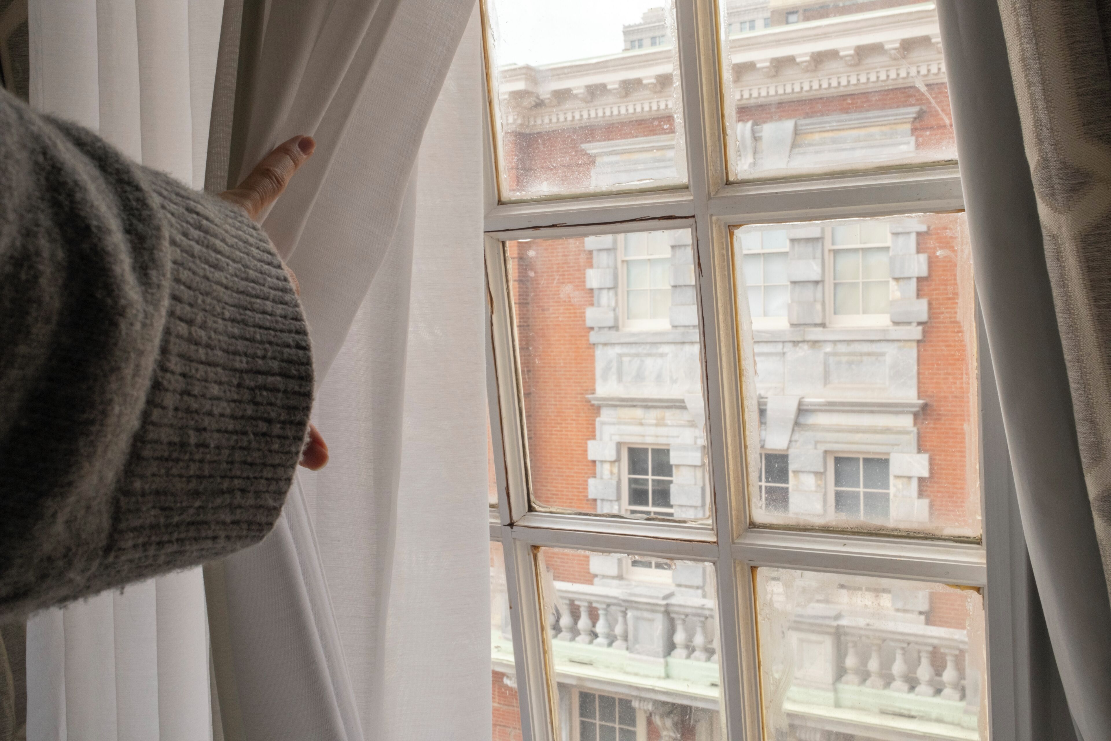 Een raam met uitzicht op een gebouw met meerdere ramen en een balkon.