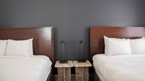 Habitación de hotel con dos camas, una pared oscura y un cabecero de madera.