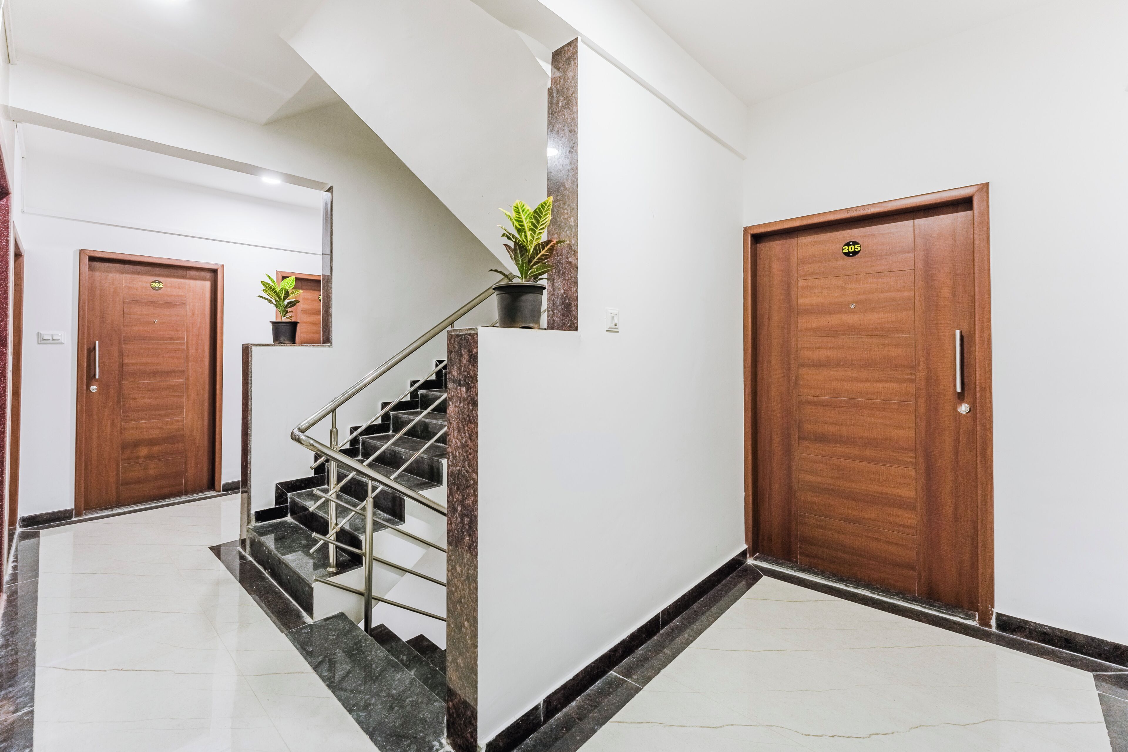 Ein modernes Interieur mit einer Marmortreppe, Holztüren und einer Kübelpflanze.