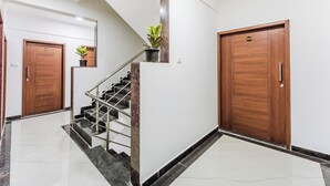 A modern interior with a marble staircase, wooden doors, and a potted plant. - Treebo Lime Light (Pune)