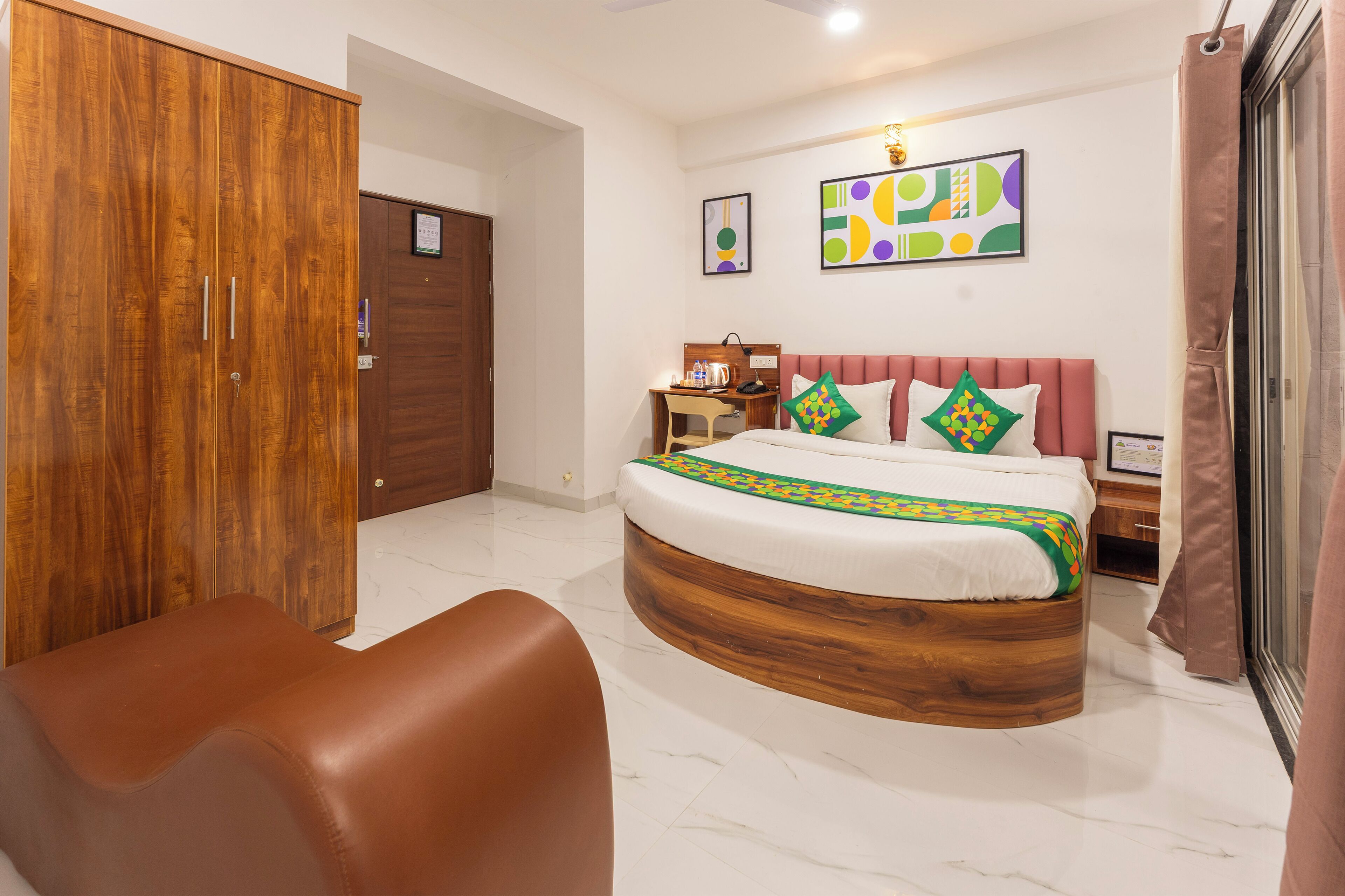 A bedroom with a bed, a wooden wardrobe, a desk, and a chair.