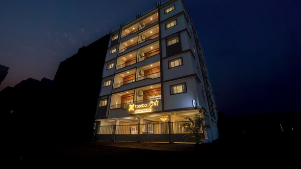 A multi-story hotel with balconies, a sign reading 'treebo treebo,' and a well-lit entrance. - Treebo Lime Light (Pune)