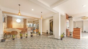 A hotel lobby with a herringbone-patterned floor, a reception desk, and several potted plants. - Treebo Lime Light (Pune)