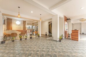 Eine Hotelhalle mit einem Fischgrätparkett, einem Empfangsbereich und mehreren Blumentöpfen.