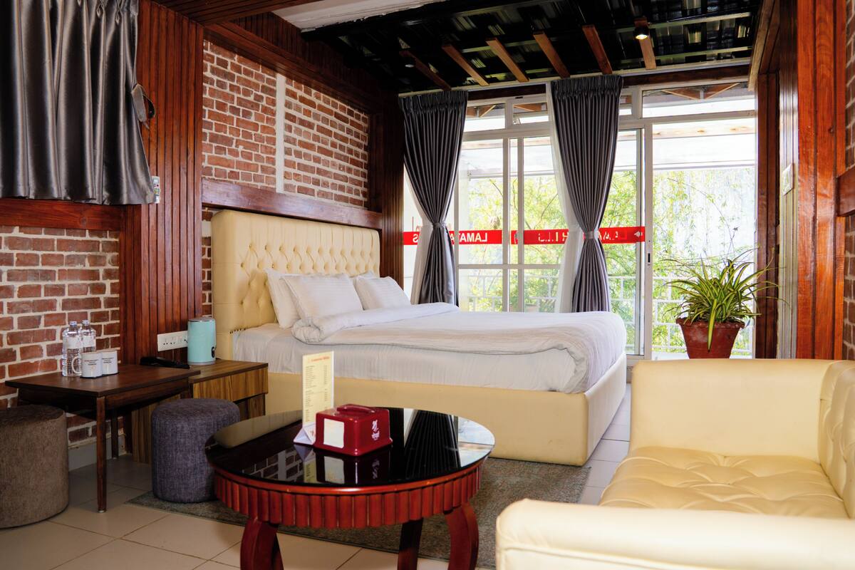 A room with a bed, a sofa, a table, and a potted plant.