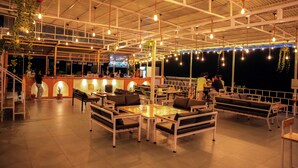 Un espace extérieur aménagé avec des tables et des chaises, un bar et des guirlandes lumineuses.