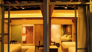 Une chambre d’hôtel avec deux lits, une petite table, une chaise, un canapé et une salle de bain équipée d’un miroir et d’un lavabo.