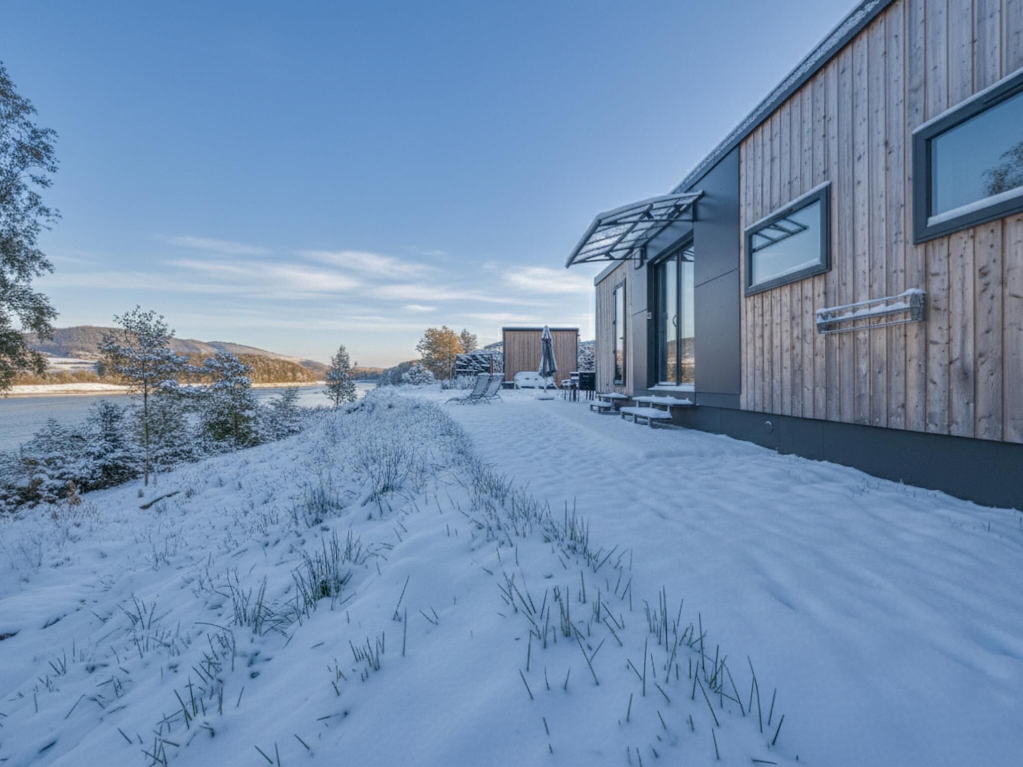 A modern building with a wooden exterior, large windows, and a snow-covered landscape.