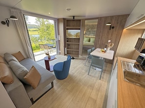 Un intérieur moderne comprenant un canapé, une table à manger, des chaises et un coin cuisine.
