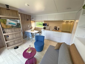 Un espace de vie compact comprenant un coin repas, une kitchenette et un coin salon.