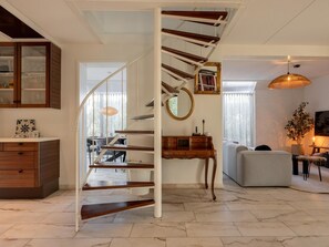 A modern living room with a spiral staircase, a dining area, and a kitchen with wooden cabinets. - Family house on a beautiful Beach Resort (Kamperland)