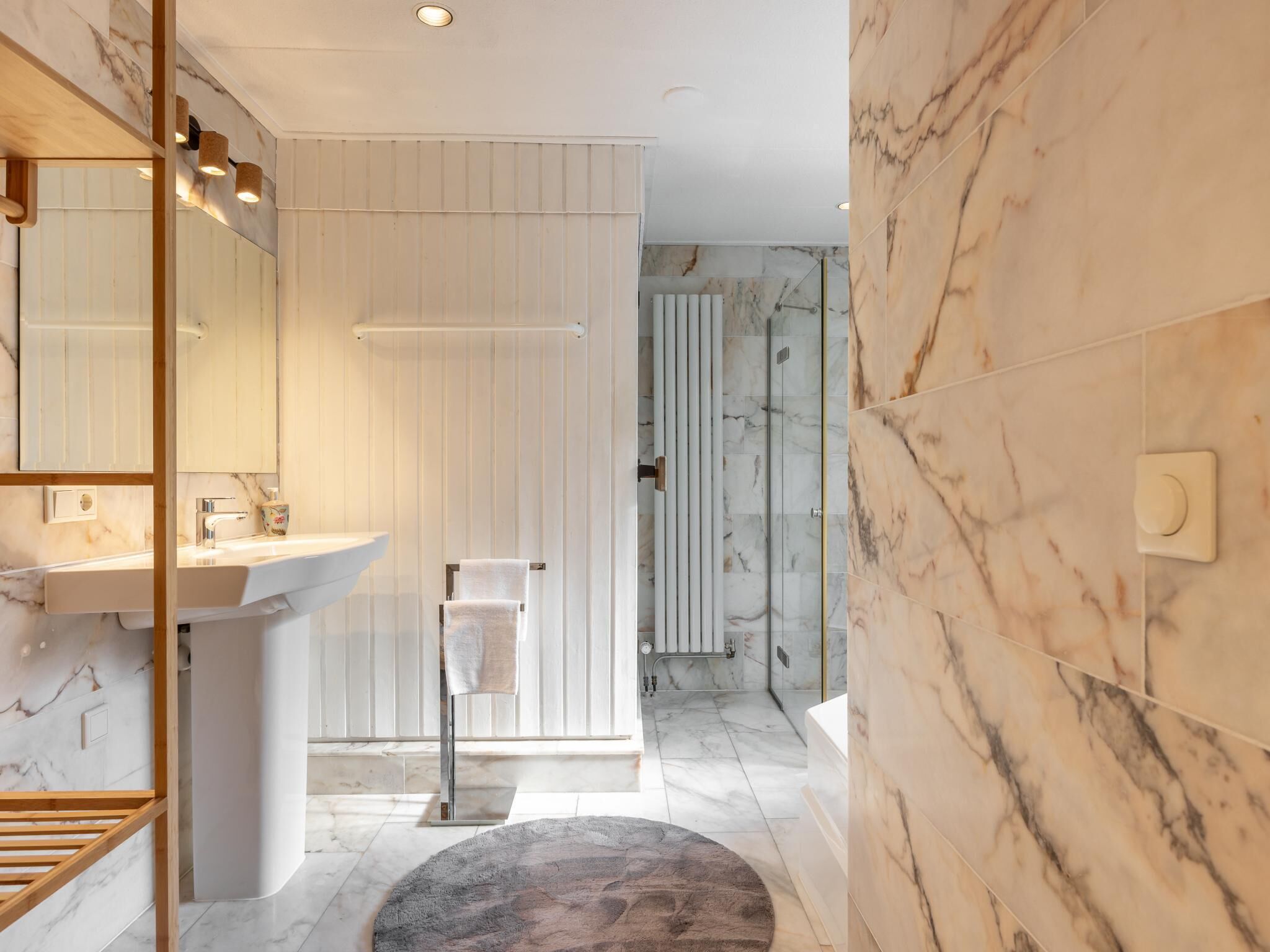 Une salle de bain moderne avec un lavabo en marbre, un porte-serviettes et un espace douche.