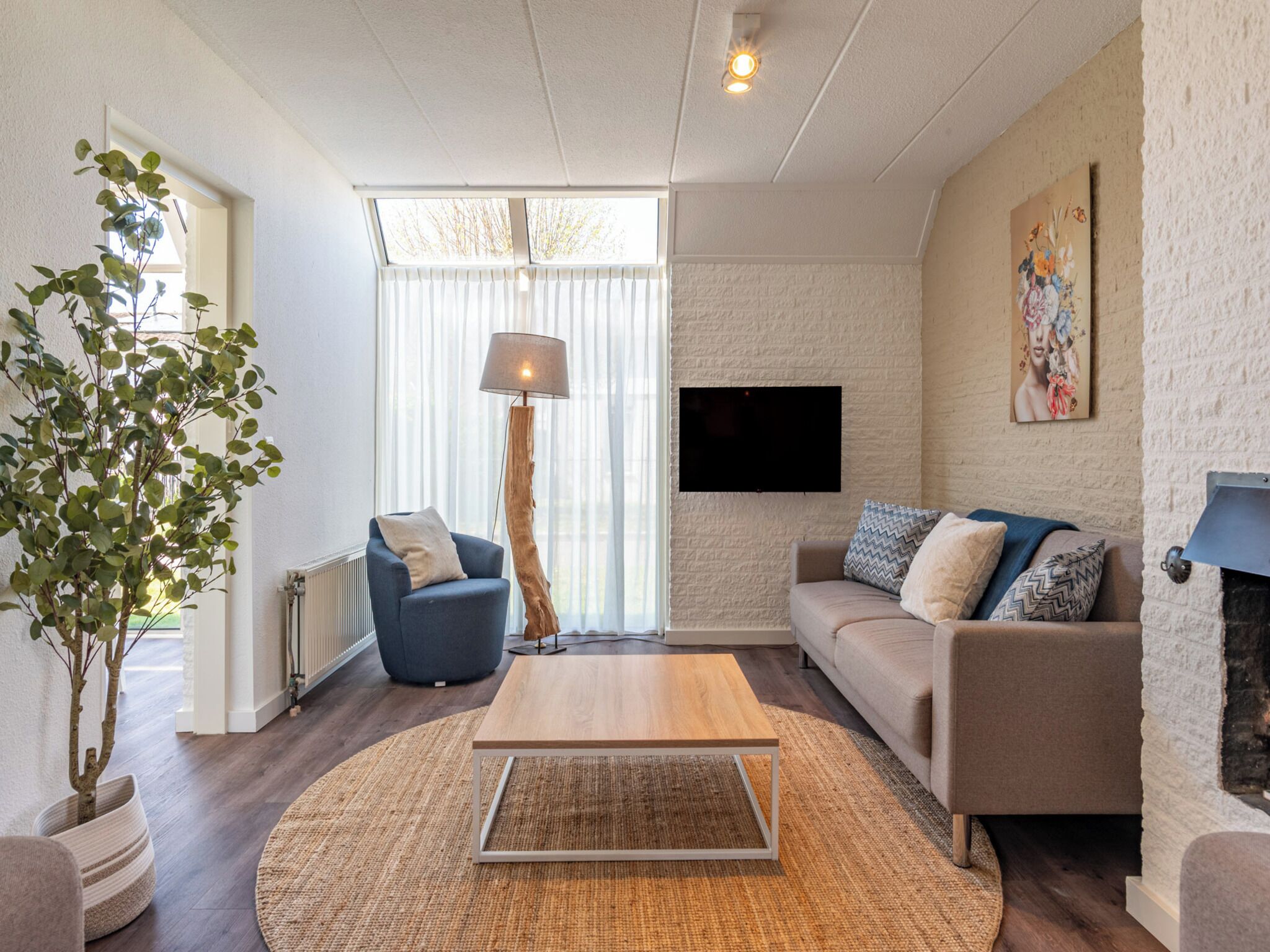 Een moderne woonkamer met een bank, een salontafel, een vloerlamp, een televisie en een open haard.