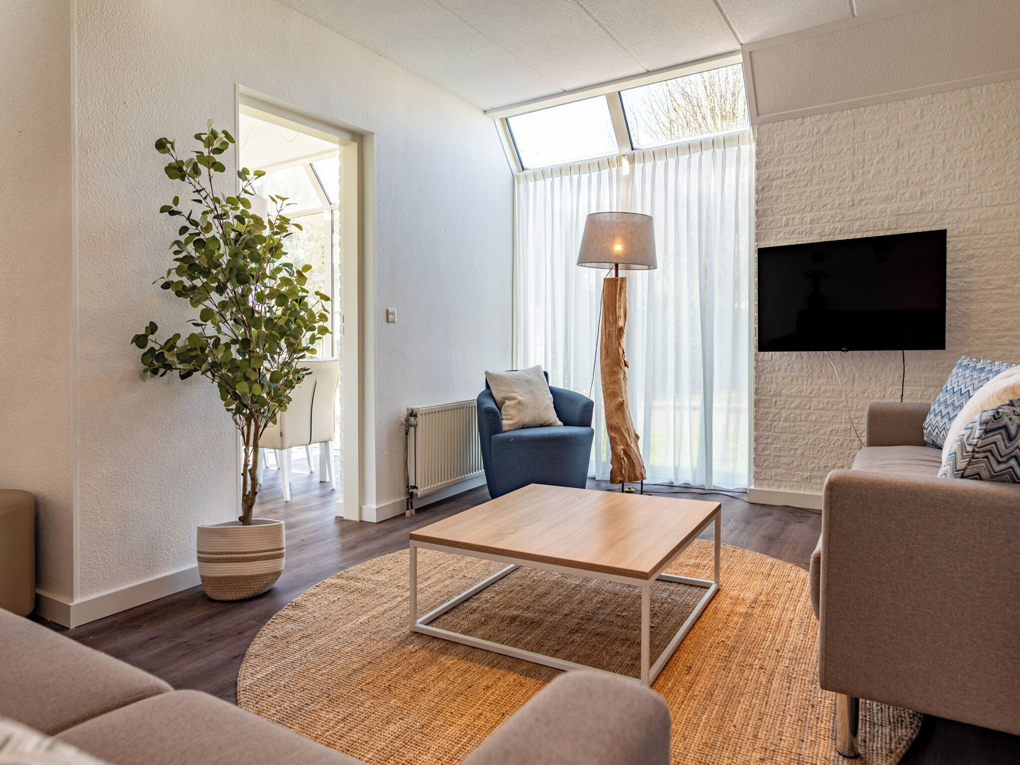 Een moderne woonkamer met een bank, een salontafel, een vloerlamp en een televisie.