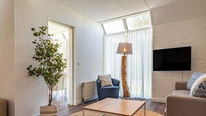 Un soggiorno moderno con un divano, un tavolino, una lampada da terra e una televisione.
