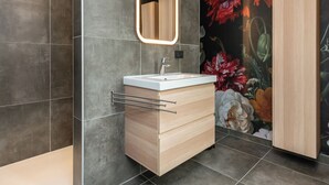 Ein modernes Badezimmer mit Waschtisch, Spiegel und gefliesten Wänden.