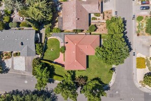 Luchtbeeld van een woongebied met een opvallend gebouw met een rode dak, omgeven door groen en kruisende wegen.