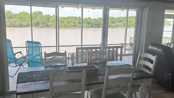 Un espace repas avec vue sur un plan d’eau, une table avec des chaises et un barbecue.