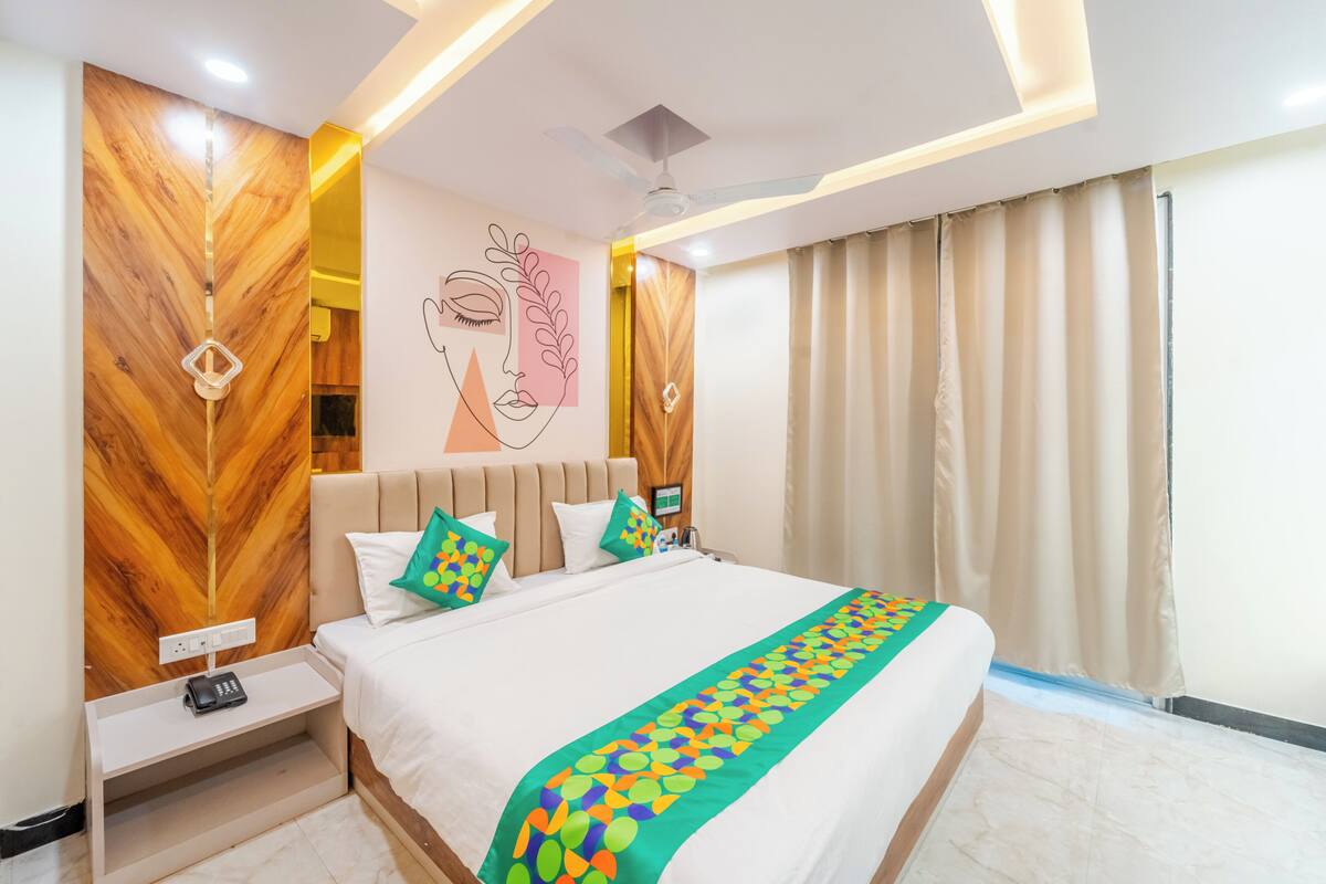 A modern hotel room with a large bed, a nightstand, a wall-mounted phone, and a ceiling fan.
