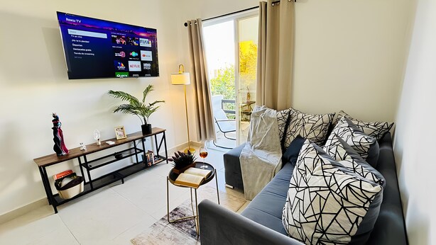 Sala de estar com televisão, sofá, mesa de apoio e planta em vaso.