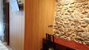 Una stanza con parete in legno, parete d'accento in pietra, una scrivania con una sedia e un televisore montato a parete.