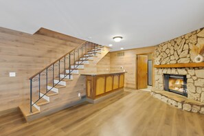 Un interior moderno con una escalera de madera, una zona de cocina y una chimenea de piedra.
