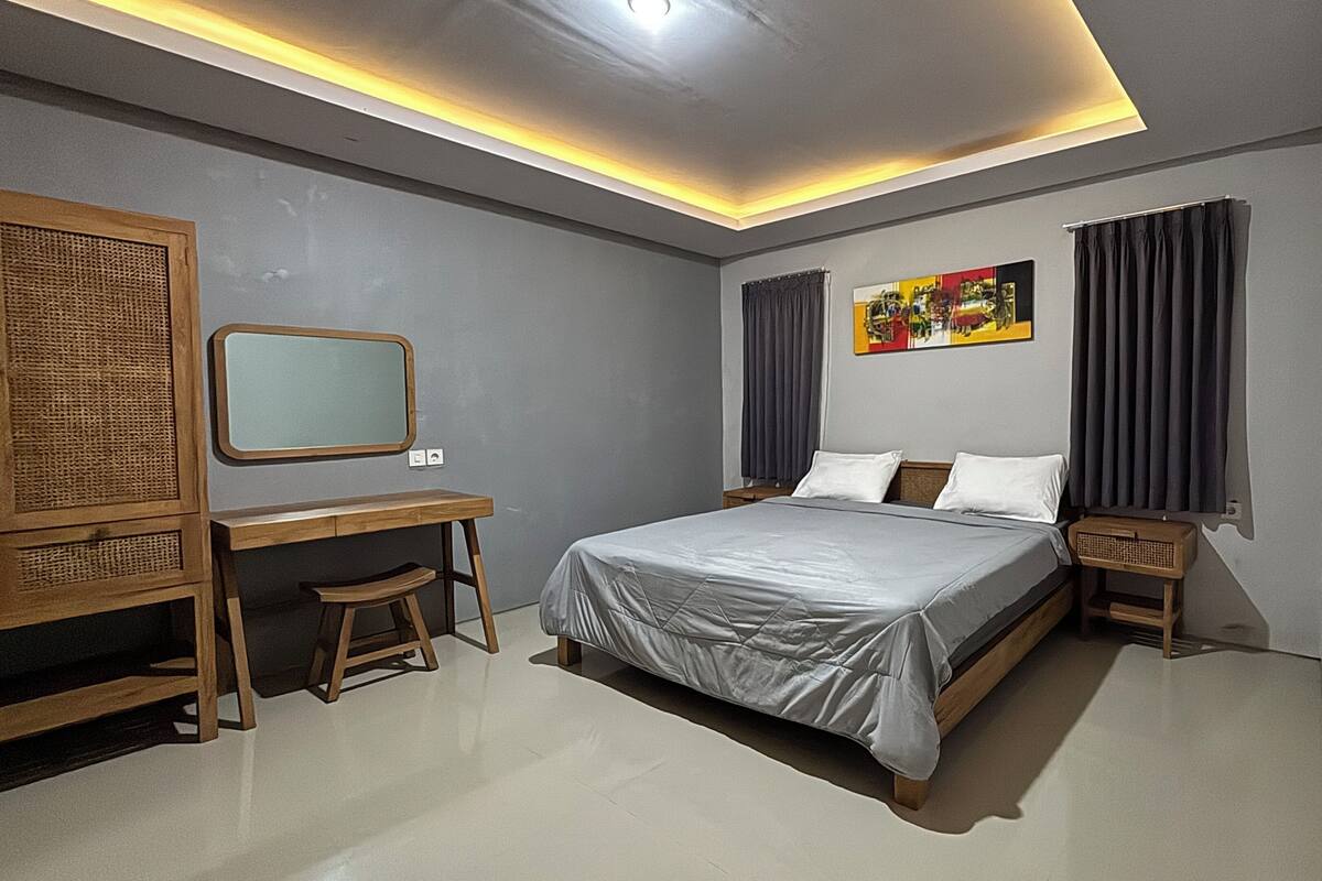 A modern bedroom with a bed, desk, and a mirror.