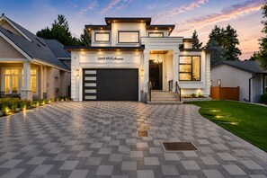 Ein modernes, zweigeschossiges Haus mit großer Garage, gepflegter Auffahrt und einem angelegten Vorgarten.