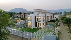 Une maison moderne à deux étages, dotée d’un toit plat, d’un vaste patio et offrant une vue sur le quartier environnant.