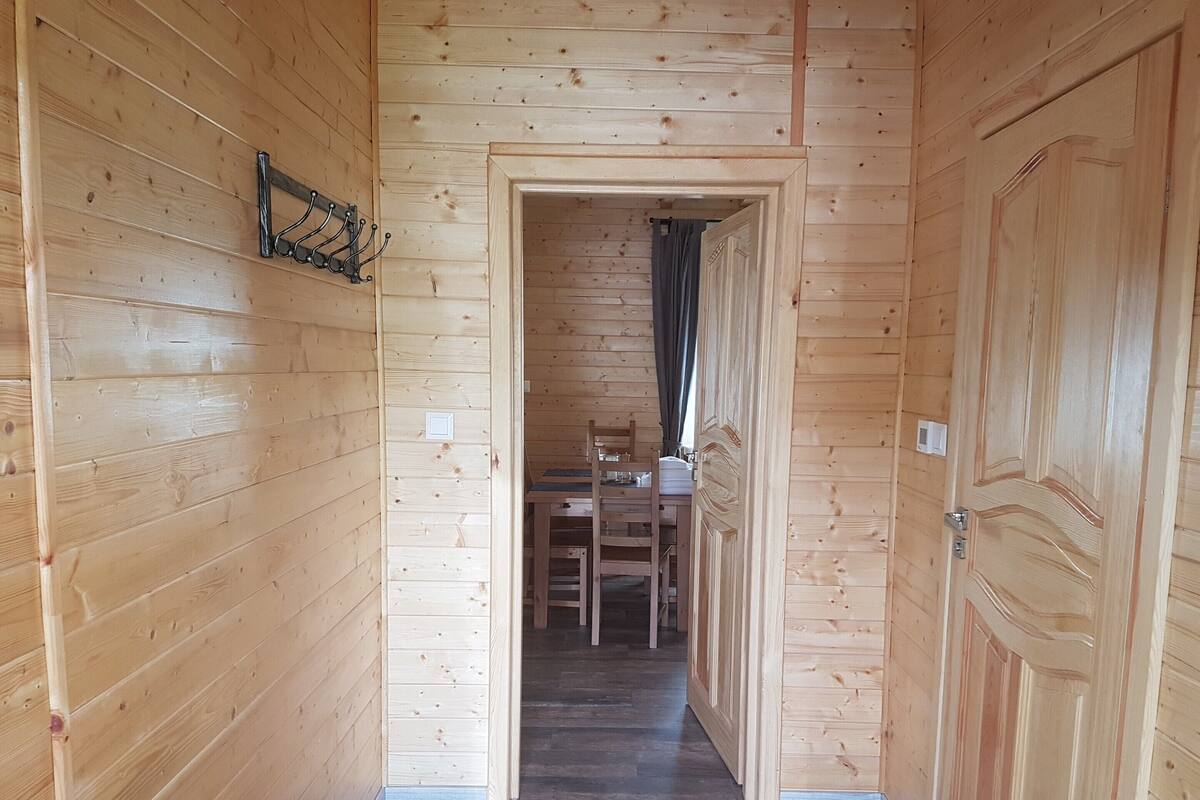 A wooden hallway with a dining area at the end, featuring a table and chairs.