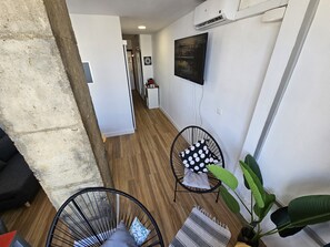 A modern interior with a wooden floor, a black chair with a polka dot pillow, a striped rug, and a large green plant. - Apartment Torremolinos Near Bajondillo Beach (Torremolinos)