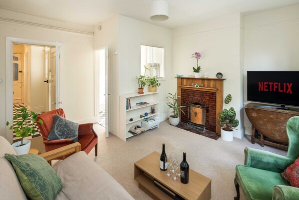 A living room with a fireplace, a television, and a bookshelf. - Charming Shepherd’s Bush Apartment (London)