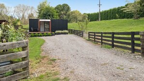 A gravel driveway leading to a modern building with a wooden fence on one side.