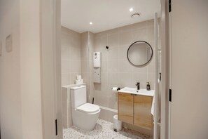 Une salle de bain moderne équipée de toilettes, d’un lavabo, d’un miroir et d’un espace douche.
