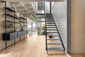 Ein modernes Interieur mit einer Treppe, Holzdielen und einer oberen Ebene mit Regalen.