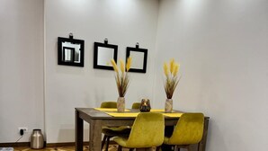 Un comedor con suelo de madera a cuadros, una mesa de madera y sillas amarillas.