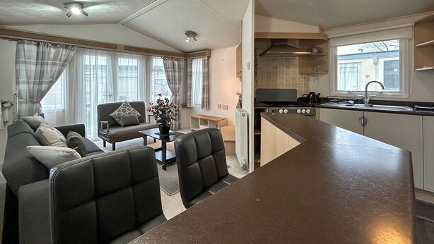 Een knus woongedeelte met een kitchenette, een bank, een eettafel en een stoel.