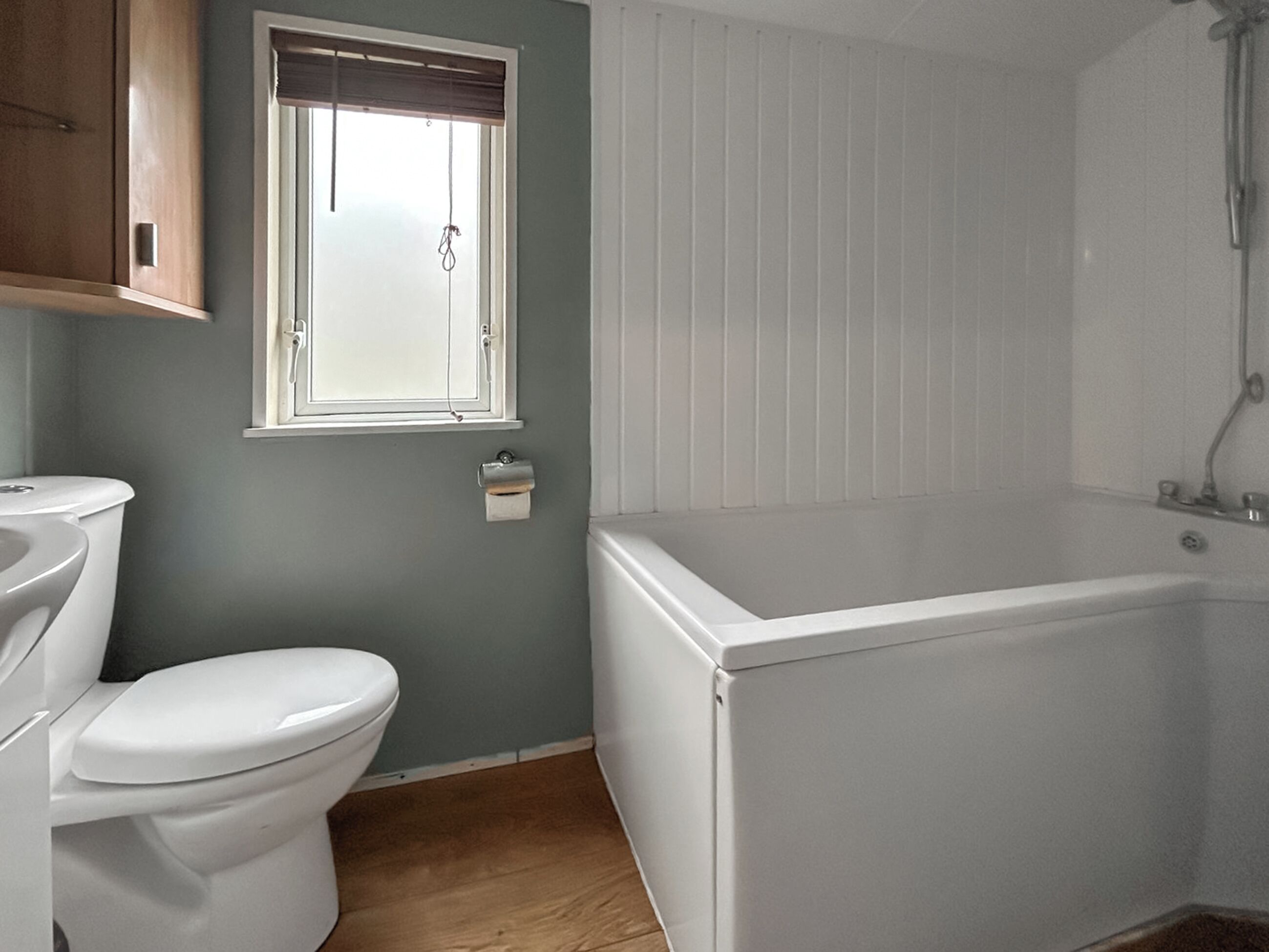 A bathroom with a toilet, a window, and a bathtub.