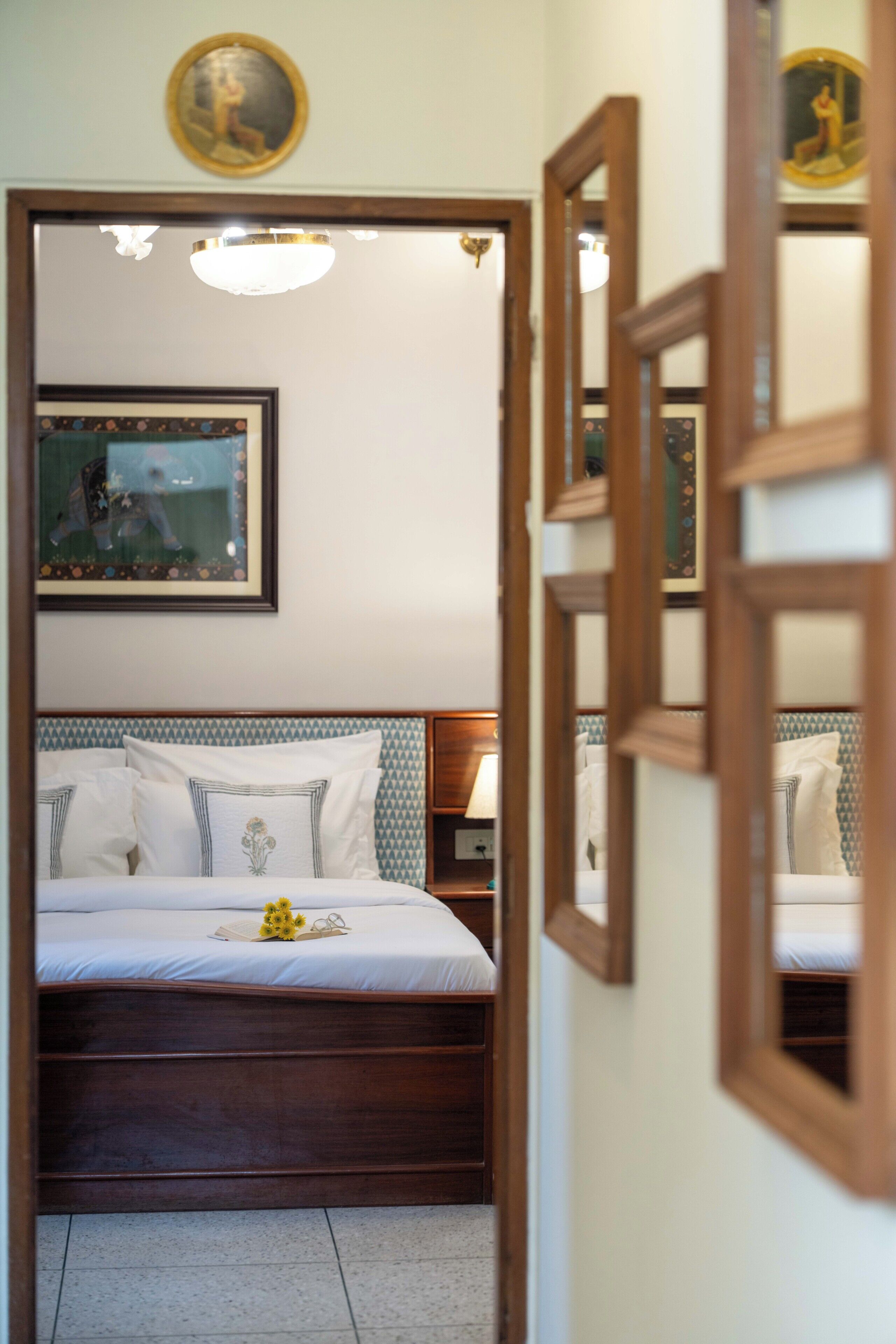 Quarto com cama, mesa de cabeceira, quadro na parede e espelho.