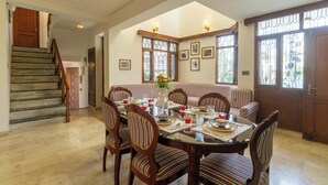 Un comedor con una mesa redonda, sillas tapizadas a rayas y una escalera que lleva a otra habitación.