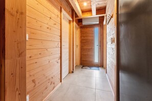A wooden interior hallway with a tiled floor, a door at the end, and a refrigerator on the right.