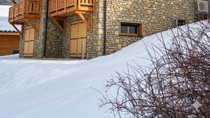 Un edificio de madera de varios pisos con detalles de piedra, balcones y un suelo cubierto de nieve.