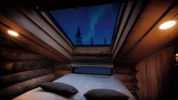 A log cabin room with a skylight, a bed with pillows, and a view of the sky. - Rukan Salonki Resort (Kuusamo)