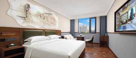 A hotel room with a large bed, a desk, a chair, a TV, and a window with a city view.