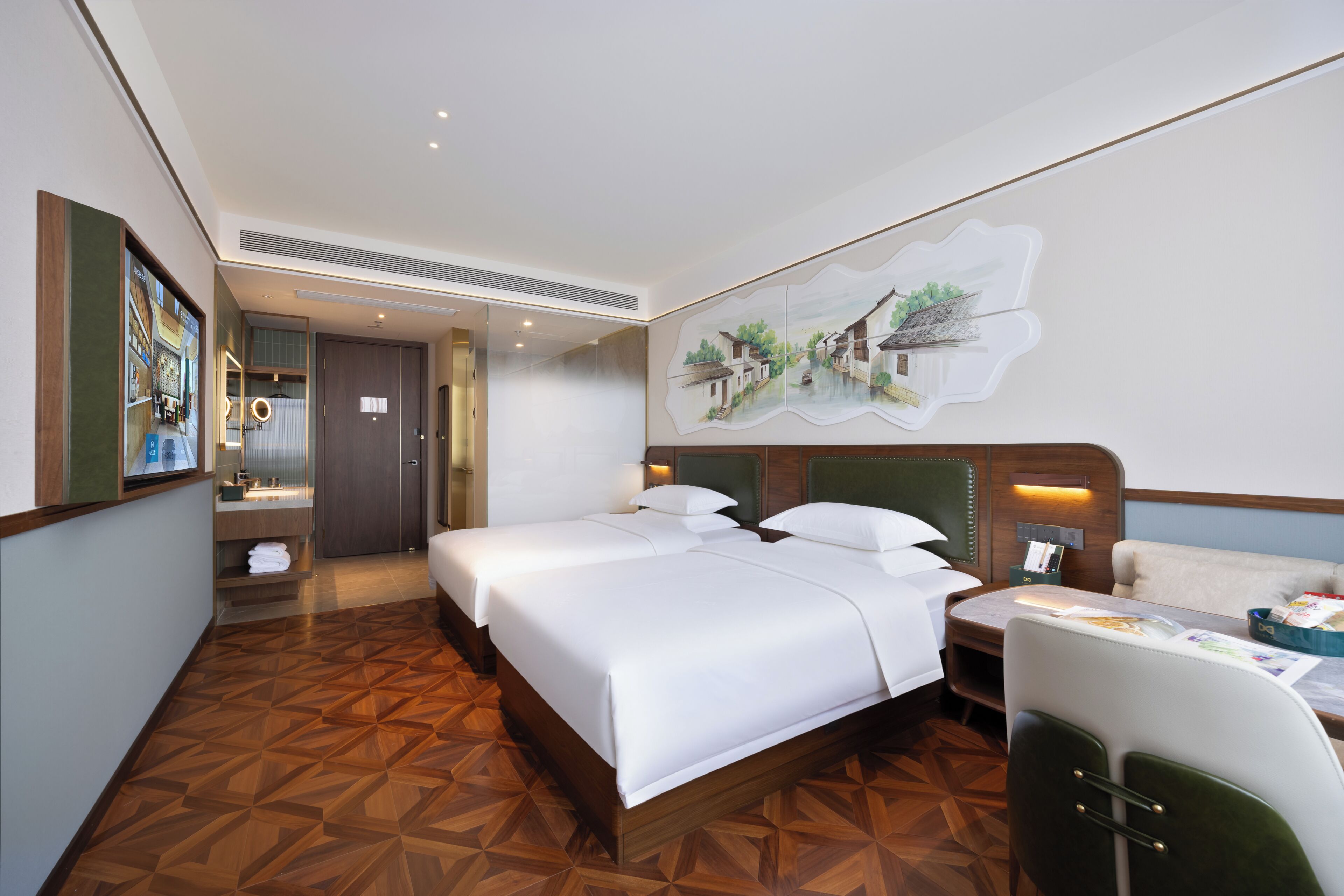 A hotel room with a large bed, a desk, a chair, a mirror, and a wall-mounted artwork.