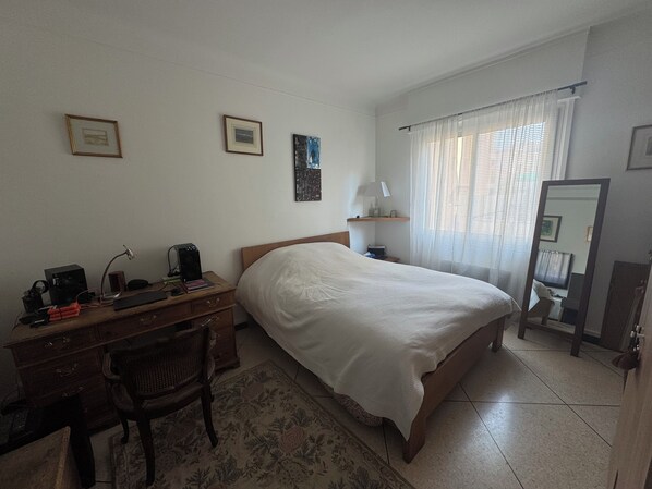 A bedroom with a bed, a desk with a computer, a chair, a lamp, and a mirror. - Charming 1-Bedroom Apartment in Alpes-Maritimes (Alpes-Maritimes)