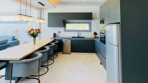 Una cocina moderna con una isla central, armarios oscuros y un horno integrado.