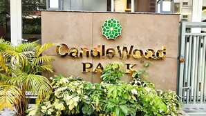 Un panneau indiquant l’entrée du parc Candlewood, avec un logo et de la verdure devant.
