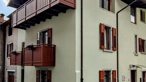 A multi-story building with balconies, a garage, and a small garden area. - Casa Relax Daone – Spacious Apartment in Central Daone (Daone)