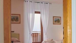 A bedroom with two beds, wooden flooring, white curtains, and a window. - Casa Relax Daone – Spacious Apartment in Central Daone (Daone)